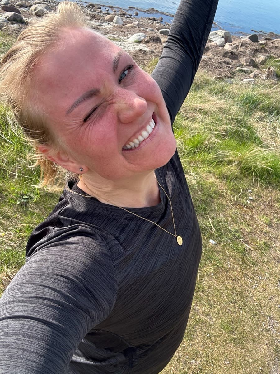 Charlotte Steinwig skrattar utomhus vid havet i träningskläder